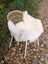 White faux fur british isles sheepskin throw draped over a wicker chair with white metal legs Mel7 45 x 29 inches