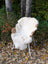 A plush white british isles sheepskin rug with subtle tan patches draped over a wicker chair measuring 45 by 29 inches