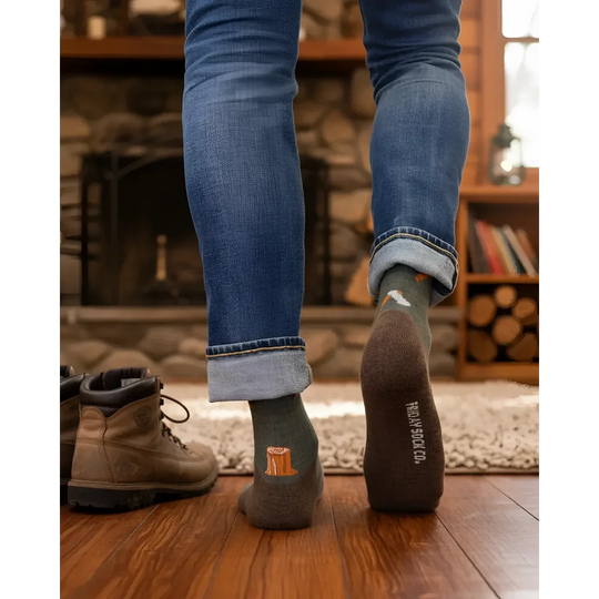 Dark olive green men’s merino wool socks with small orange tree stump and treasure sock co branding on heel for hiking
