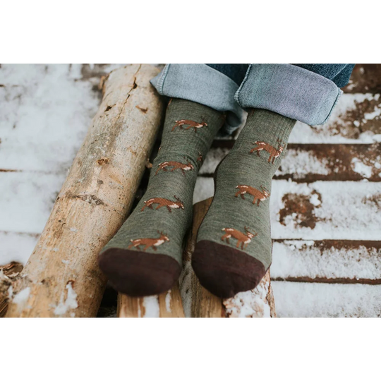 Men’s olive green merino wool socks with brown deer prints and dark brown toe caps worn with rolled-up jeans