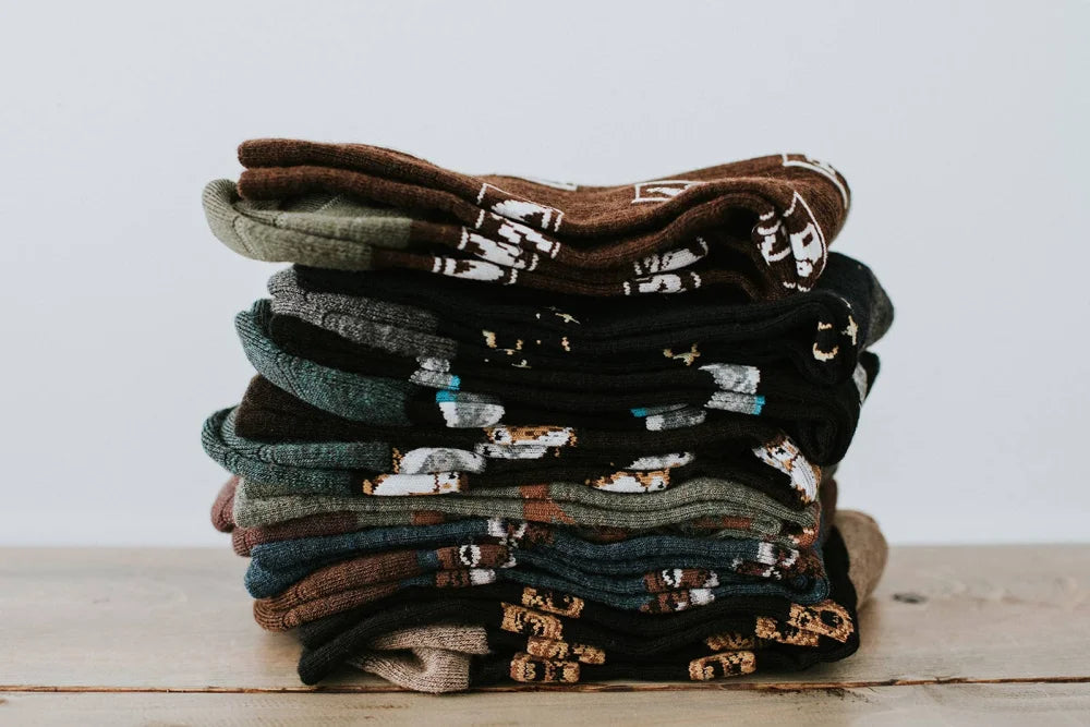 A stack of men’s owl merino wool socks in earthy tones featuring warm breathable wool socks with animal designs