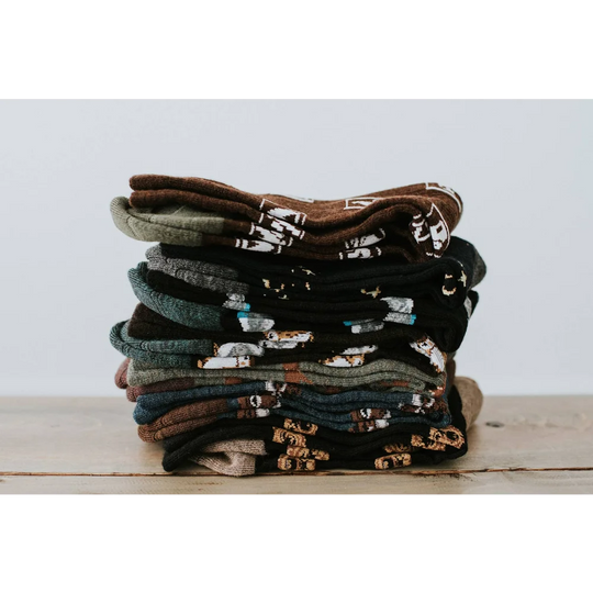 A stack of men’s owl merino wool socks in earthy tones featuring warm breathable wool socks with animal designs