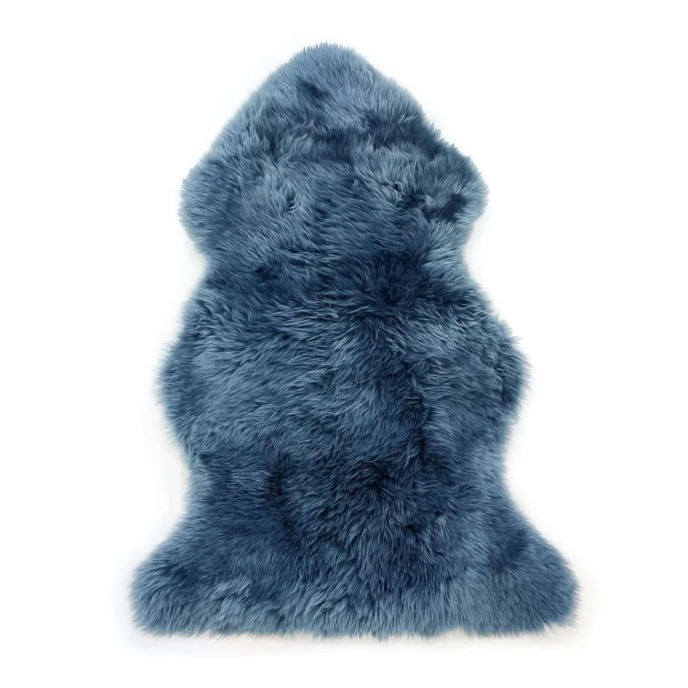 A plush deep blue dyed merino sheepskin rug with soft fluffy texture and natural irregular edges