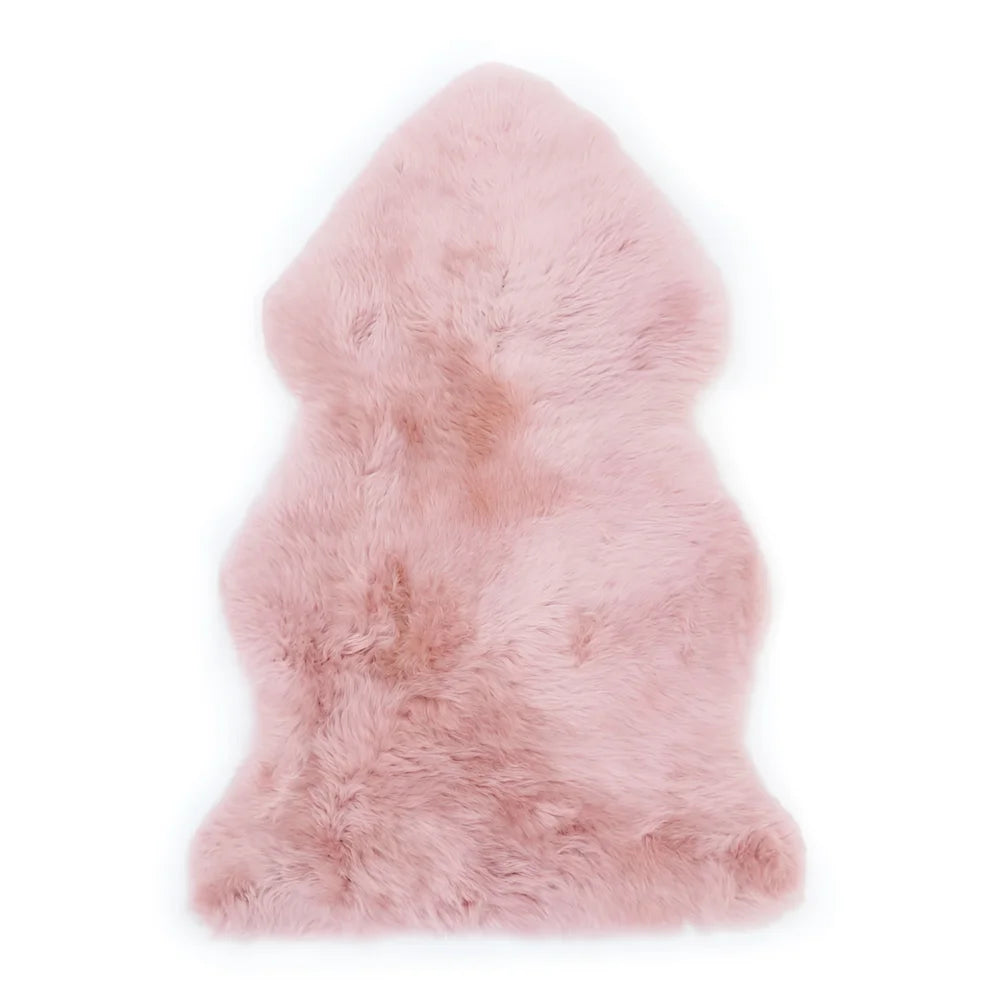 Soft pink dyed merino sheepskins with natural fluffy texture and irregular edges for cozy home decor