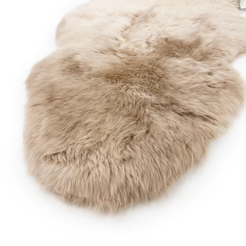A soft natural beige dyed merino sheepskin rug with plush fluffy texture and irregular edges from dyed merino sheepskins
