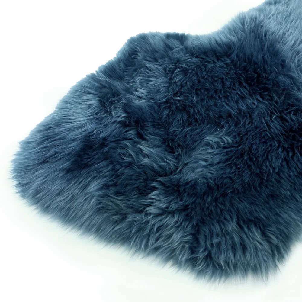 A plush deep blue dyed merino sheepskin rug with soft fluffy texture and natural fur edges perfect for cozy decor