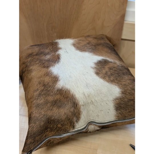 Brown and white cowhide mini moo cushion with visible zipper edge by angus oliver canada for cozy decor