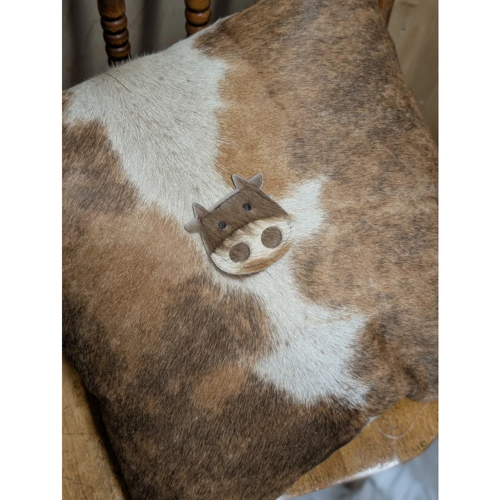 A mini moo angus oliver double sided cowhide cushion with brown white cow pattern and cute stitched cow face from canada