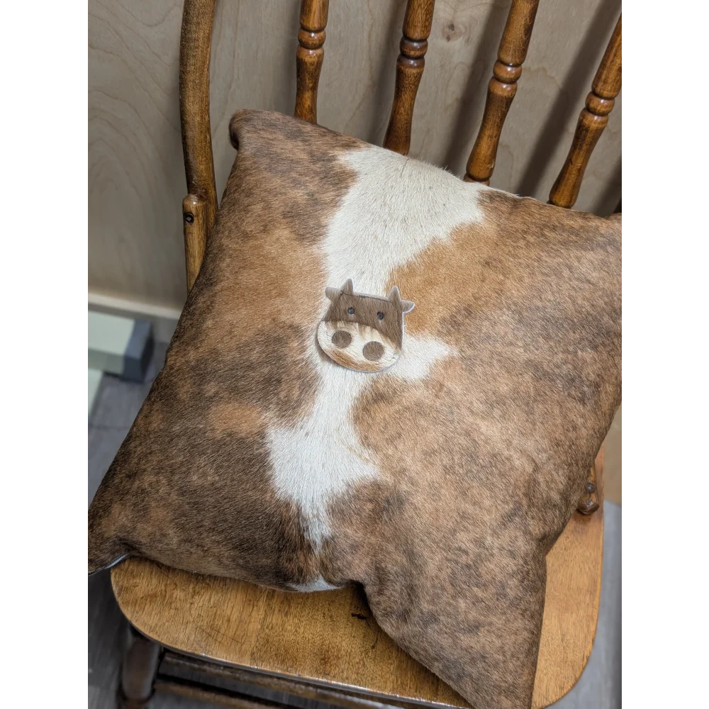 Brown and white mini moo double sided cowhide cushion with stitched cow face appliqué by angus oliver canada