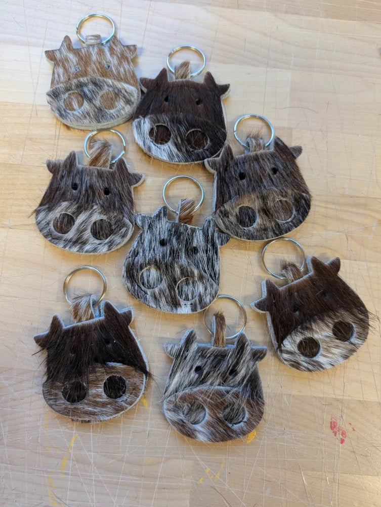 Mini moo cow-shaped keychains from angus oliver canada made with brown and white stitched cowhide details