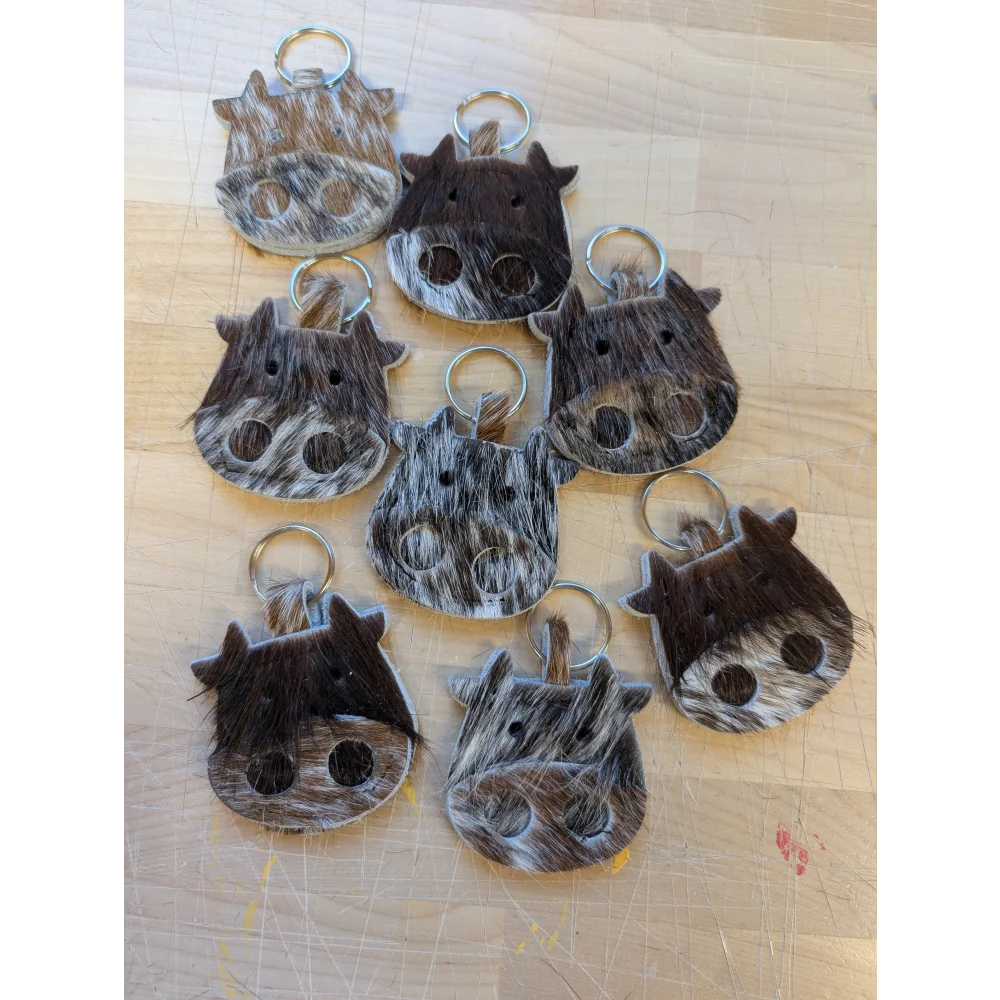 Mini moo cow-shaped keychains from angus oliver canada made with brown and white stitched cowhide details