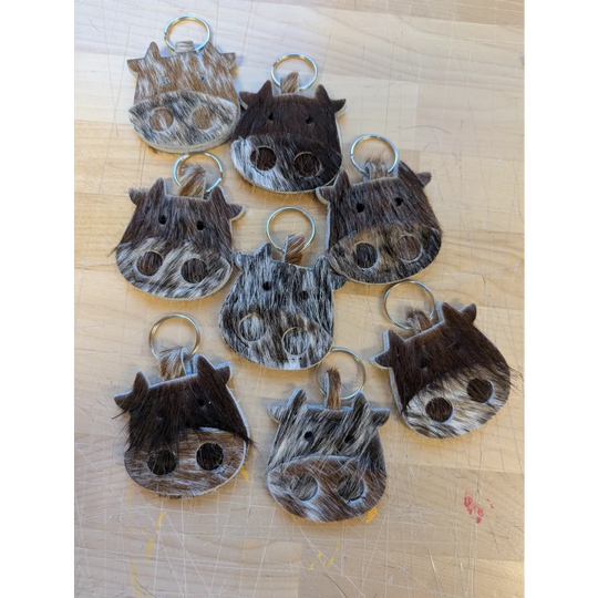 Mini moo cow-shaped keychains from angus oliver canada made with brown and white stitched cowhide details