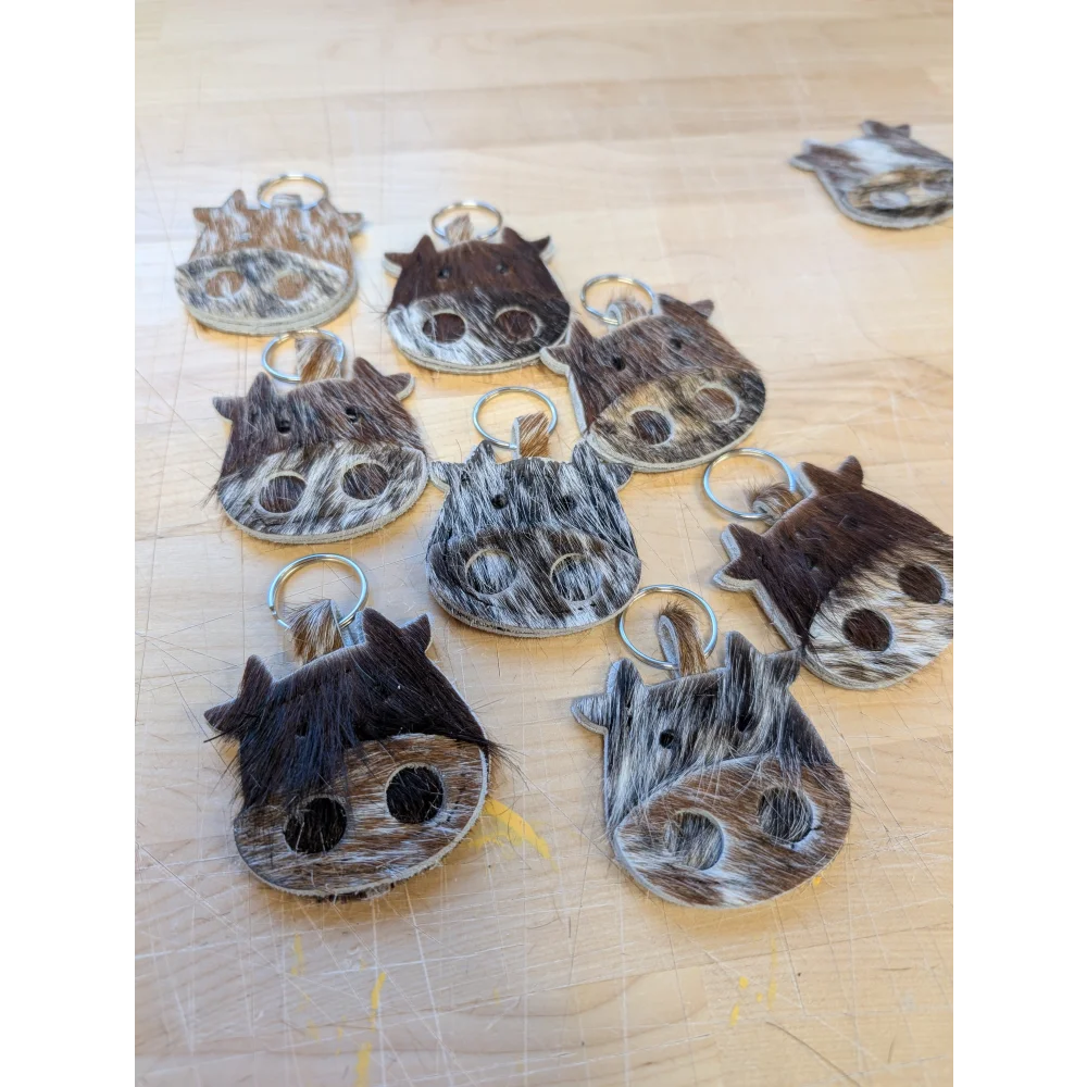 Brown and white cow shaped mini moo keychains made of textured hide with metal rings by angus oliver canada