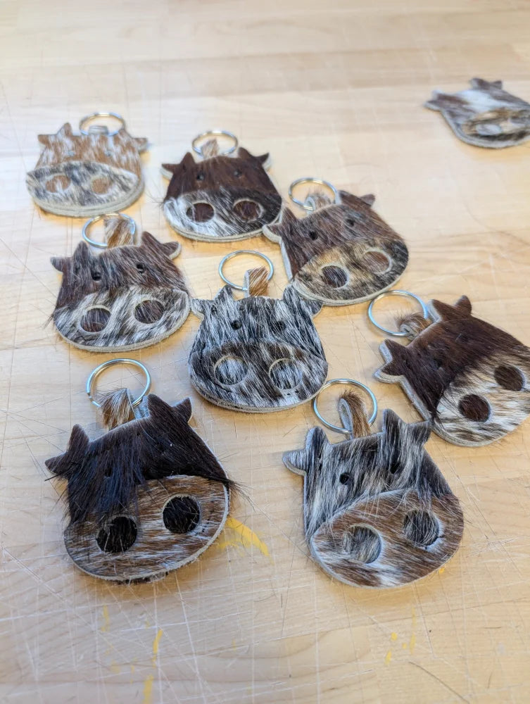 Brown and white cow shaped mini moo keychains made of textured hide with metal rings by angus oliver canada