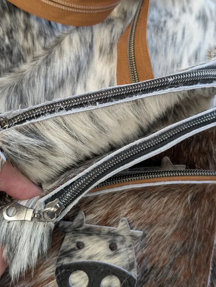 Moocoin purse by angus oliver canada featuring cow print faux fur, tan leather straps, and silver zippers coin purse