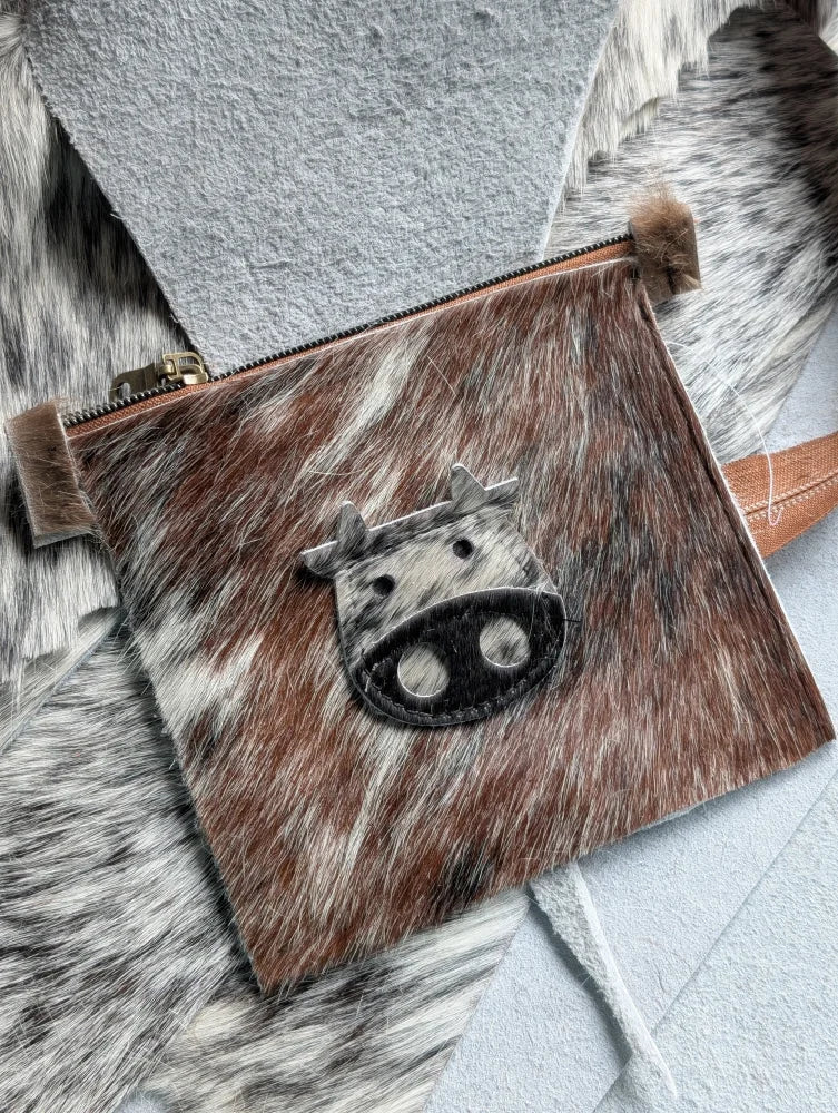 Brown and white cowhide coin purse with black stitched cow face appliqué from angus oliver canada