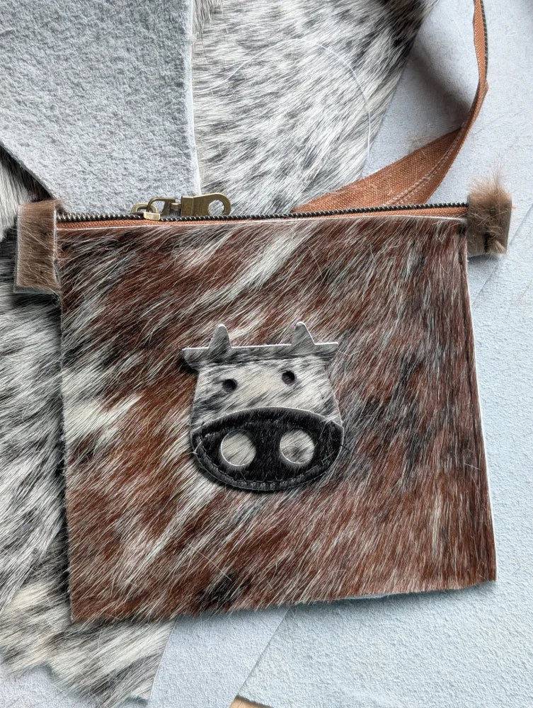 Brown and white cowhide coin purse with black stitched cow face appliqué by angus oliver canada