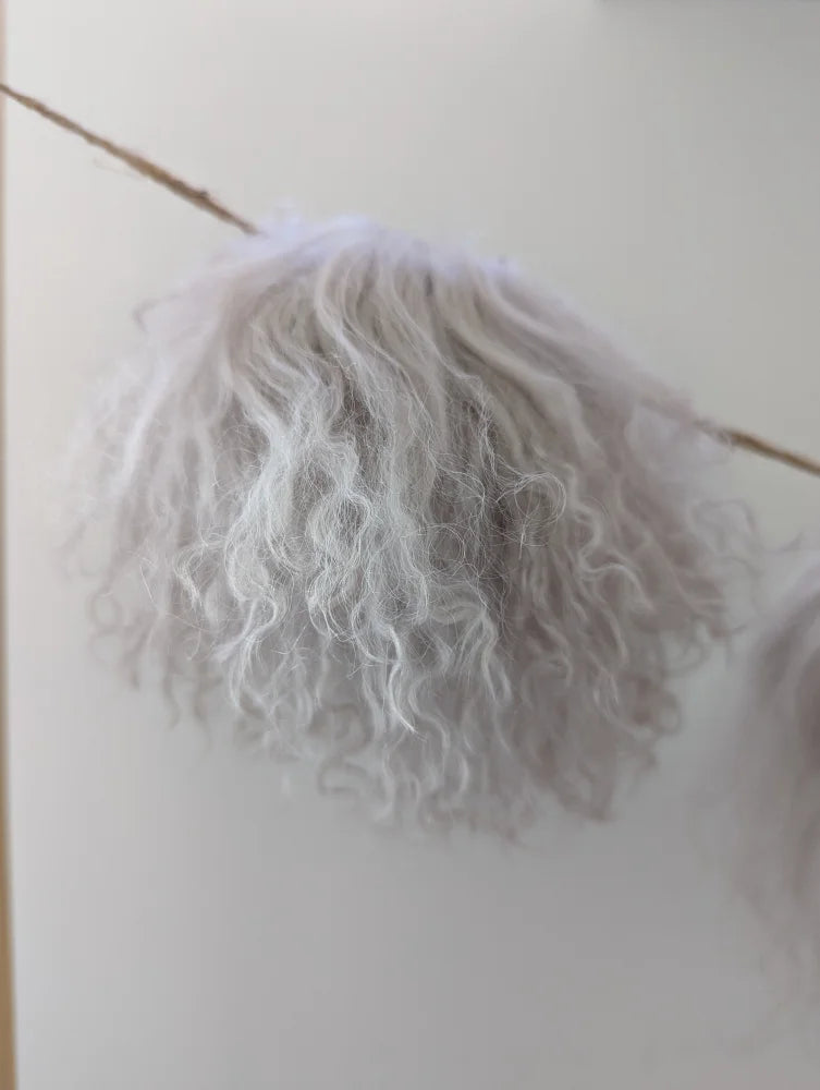 White curly mushroom sheepskin pom hanging from wooden stick