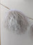 White curly mushroom sheepskin pom hanging from wooden stick
