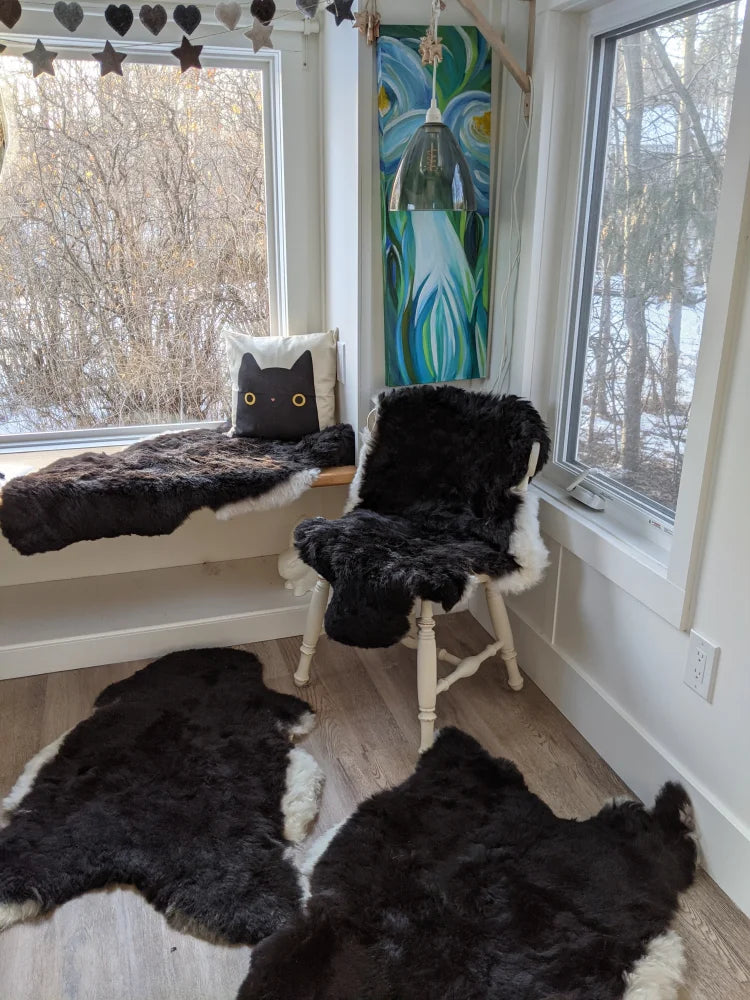 Black and white faux fur cat-shaped rug with fluffy texture made of wool icelandic sheepskins placed on the floor
