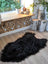 Black fluffy natural blacky long wool icelandic sheepskin rug with dense fur on light wood floor