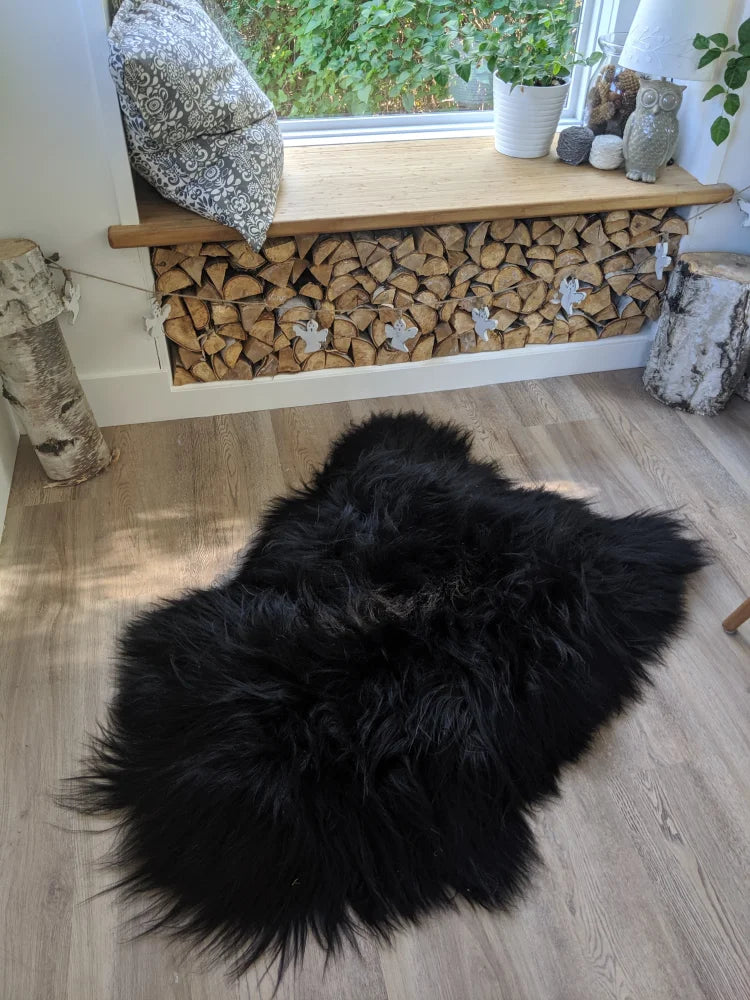 Black fluffy sheepskin rug with long wool icelandic fibers and natural irregular shape perfect for cozy decor
