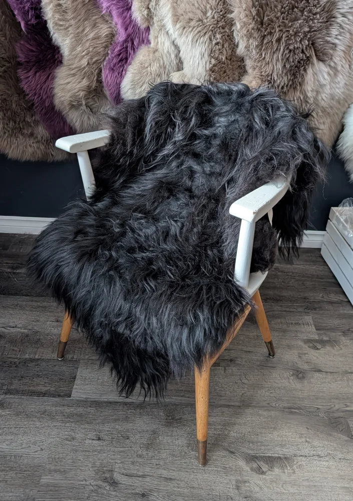 Black thick wool icelandic sheepskins chair cover with white arms and wooden legs featuring long wool icelandic fleece