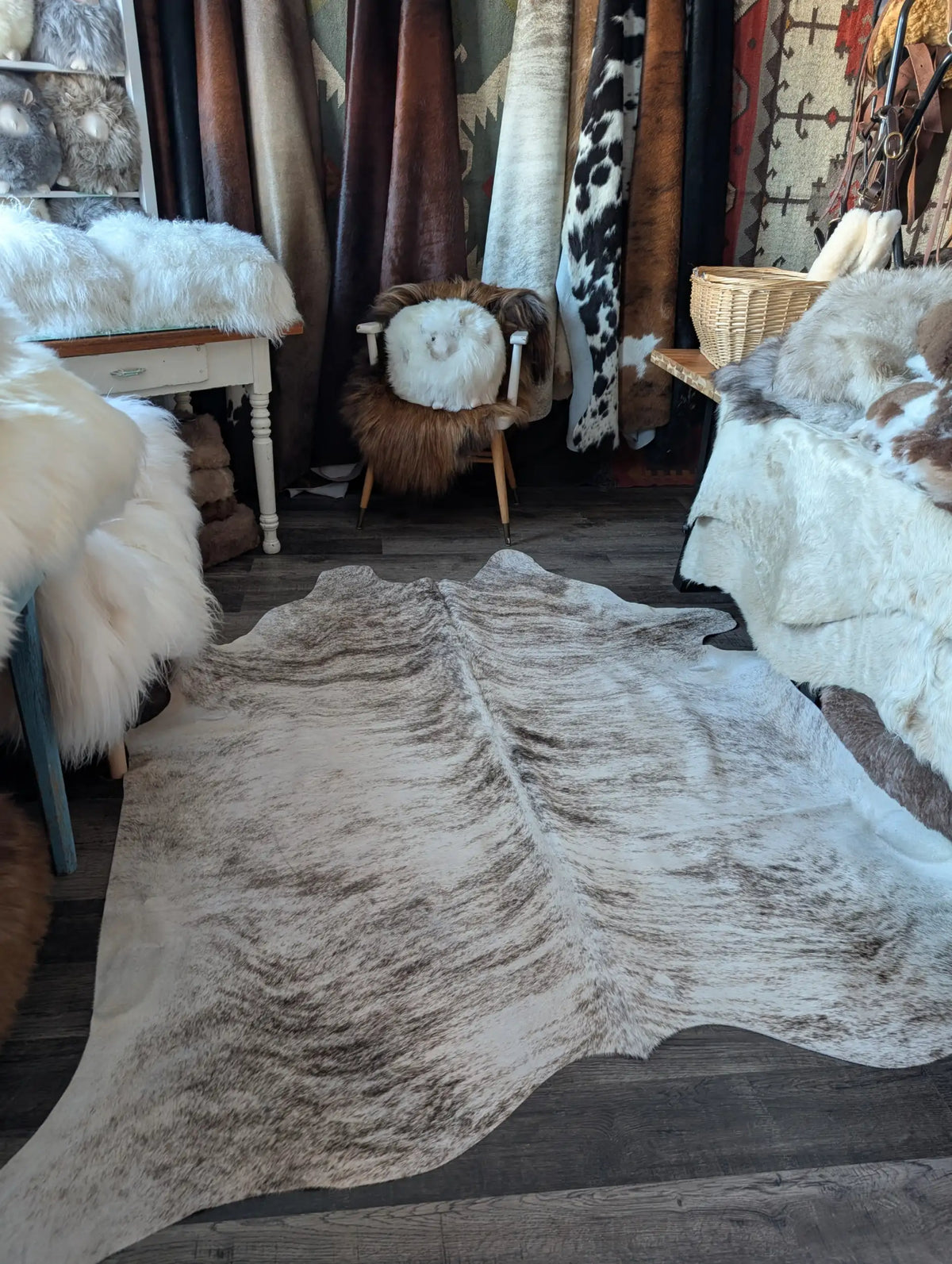 A natural, full-sized cowhide rug with a mottled pattern of white and brown fur.