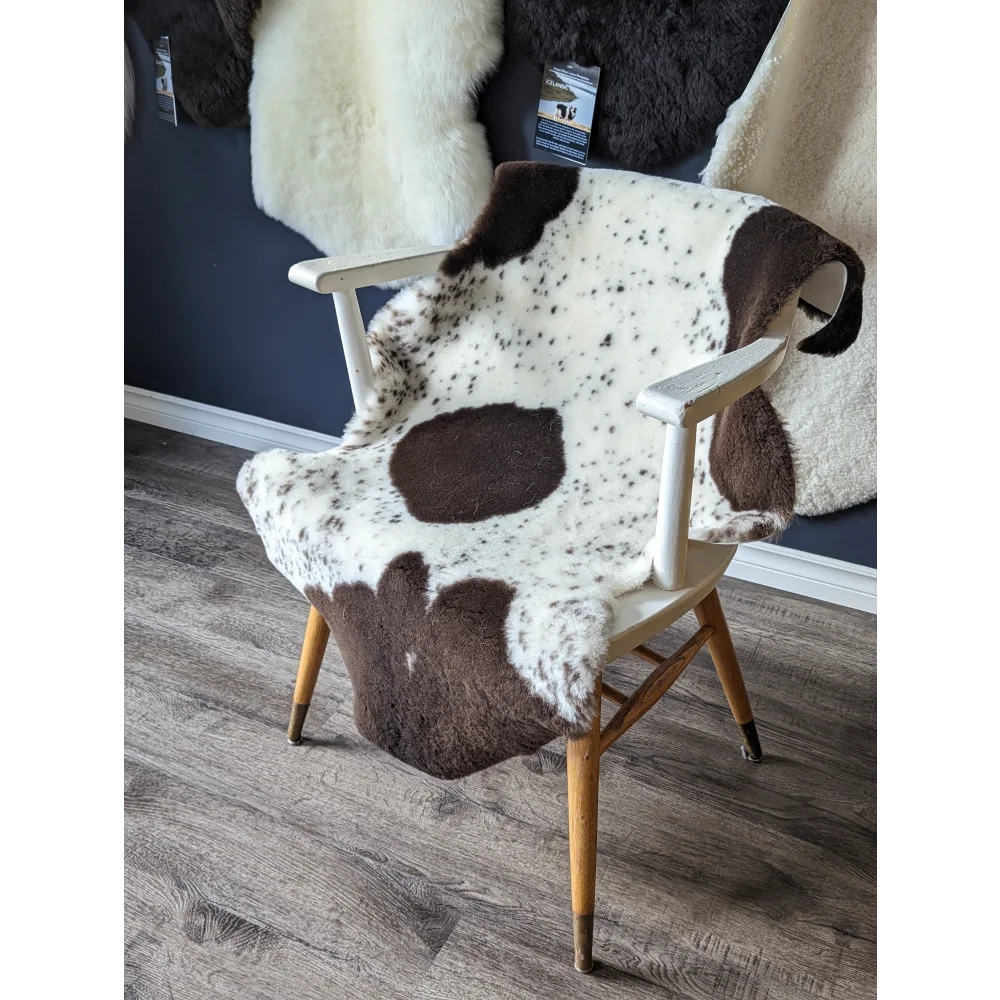 Spotted cowhide chair with gorgeous merino sheepskins and wooden legs
