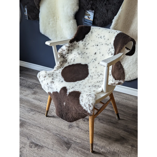 Spotted cowhide chair with gorgeous merino sheepskins and wooden legs