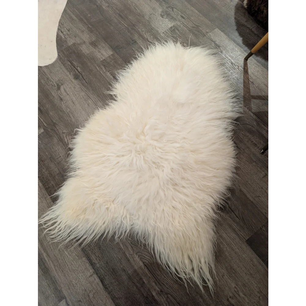 A plush off-white icelandic sheepskin rug with long soft fur lying on a dark wood floor natural white icelandic sheepskin