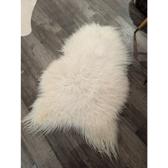 A plush off-white icelandic sheepskin rug with long soft fur lying on a dark wood floor natural white icelandic sheepskin