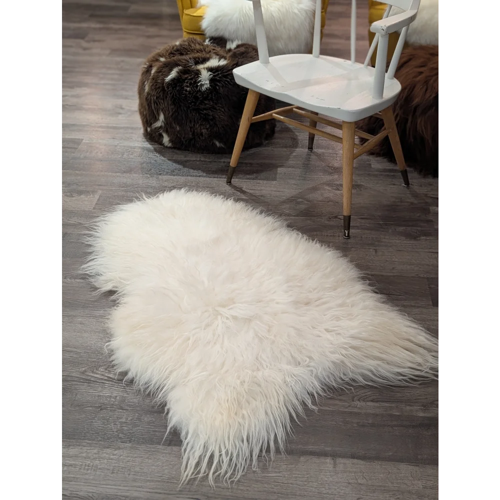 A plush natural white icelandic sheepskin rug with long fluffy fibers on a dark wood floor perfect for cozy spaces