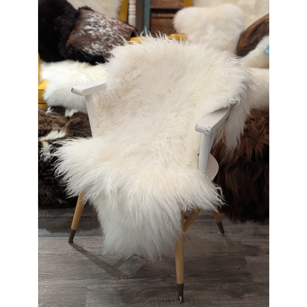 Natural white icelandic sheepskin throw draped over white wooden chair with light wood legs perfect for cozy decor