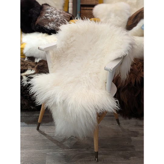 Natural white icelandic sheepskin throw draped over white wooden chair with light wood legs perfect for cozy decor