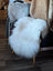 A plush fluffy natural white icelandic sheepskin rug with long wool icelandic texture draped over a chair