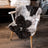 A plush natural black icelandic sheepskin rug with white spots draped over a modern white chair with wooden legs