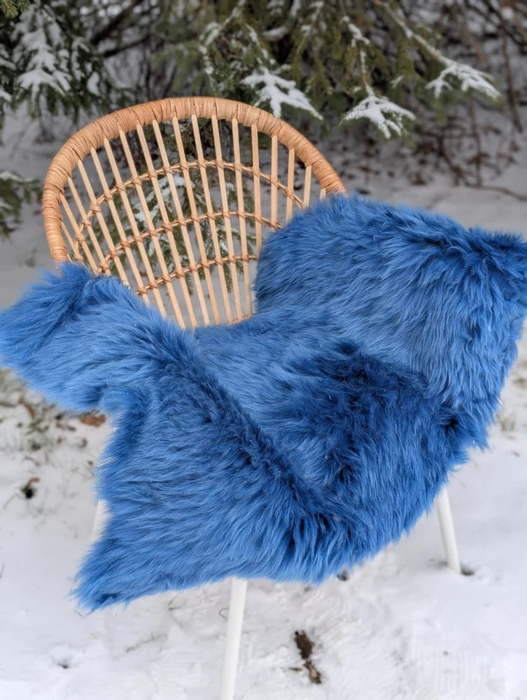 Vibrant blue merino sheepskin faux fur throw blanket draped over wicker chair perfect for mid october cozy vibes