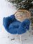 A vibrant blue merino sheepskin fluffy chair cover draped over a woven wicker chair perfect for mid october cozy vibes