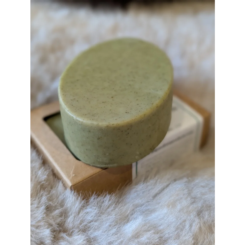 Olive green nettle and tea tree soap bar with speckled texture on wooden box