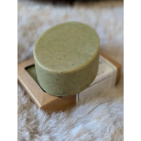 Olive green nettle and tea tree soap bar with speckled texture on wooden box
