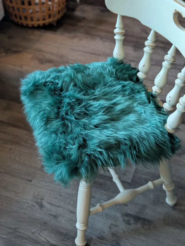 Teal faux fur sheepskin chair pad in gorgeous green merino with white wooden legs