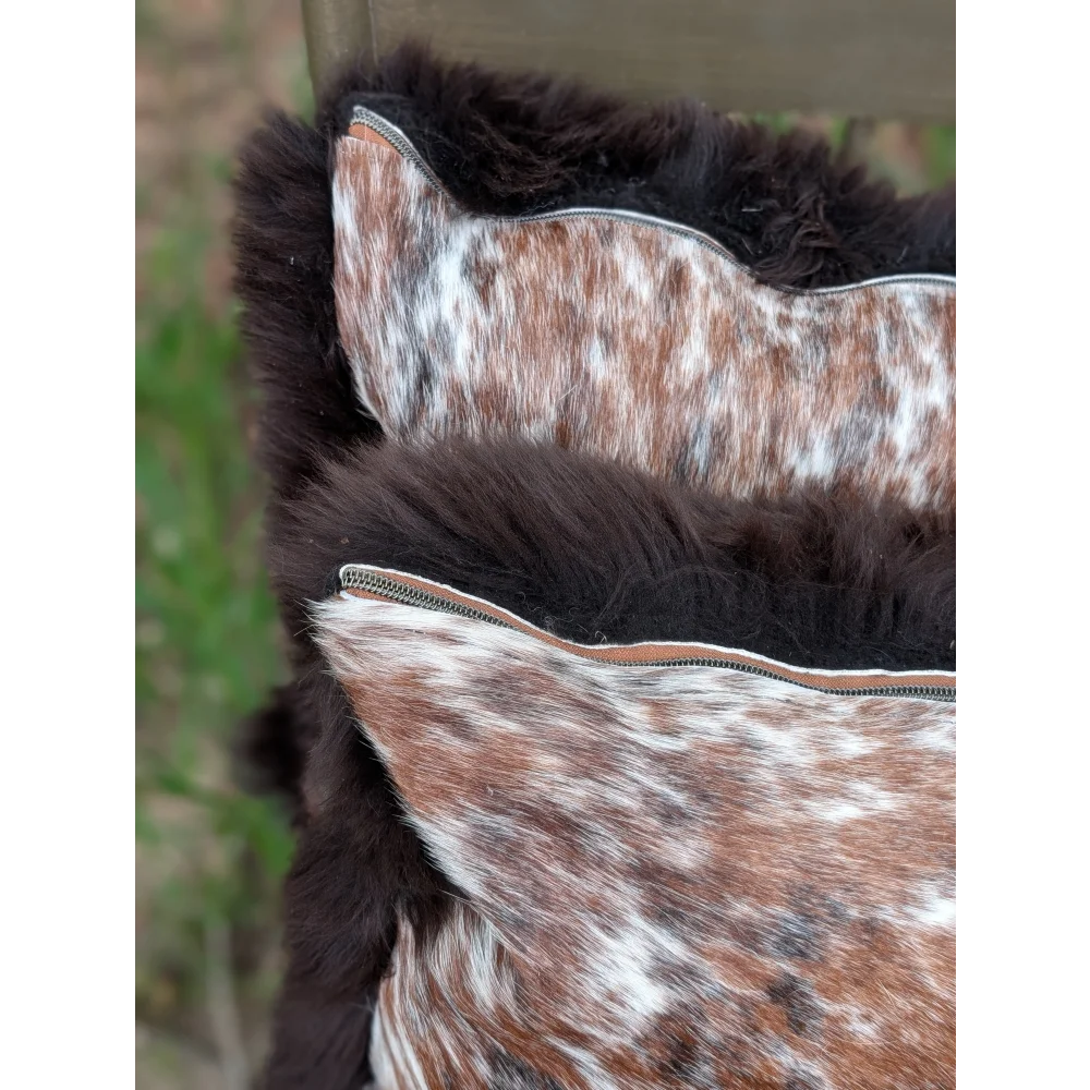 Brown and white cowhide cushions with plush dark fur trim perfect for cozy british sheepskin decor