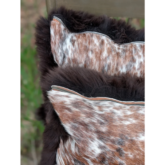 Brown and white cowhide cushions with plush dark fur trim perfect for cozy british sheepskin decor