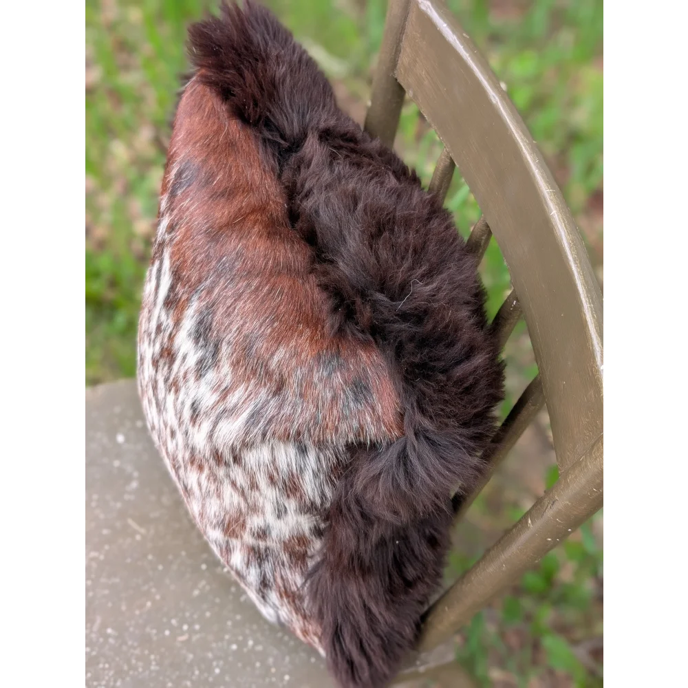 A cozy plush winter hat made of soft brown and white cowhide fur with dark brown fluffy trim perfect for brazilian cowhide cushions
