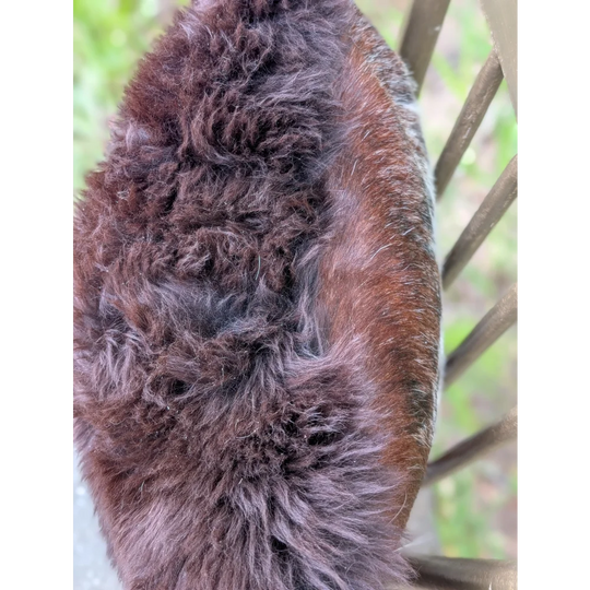 A plush dark brown faux fur hat with soft texture complements handmade british sheepskin and brazilian cowhide cushions