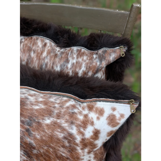 Brown and white spotted cowhide cushion with dark brown faux fur trim perfect for british sheepskin decor