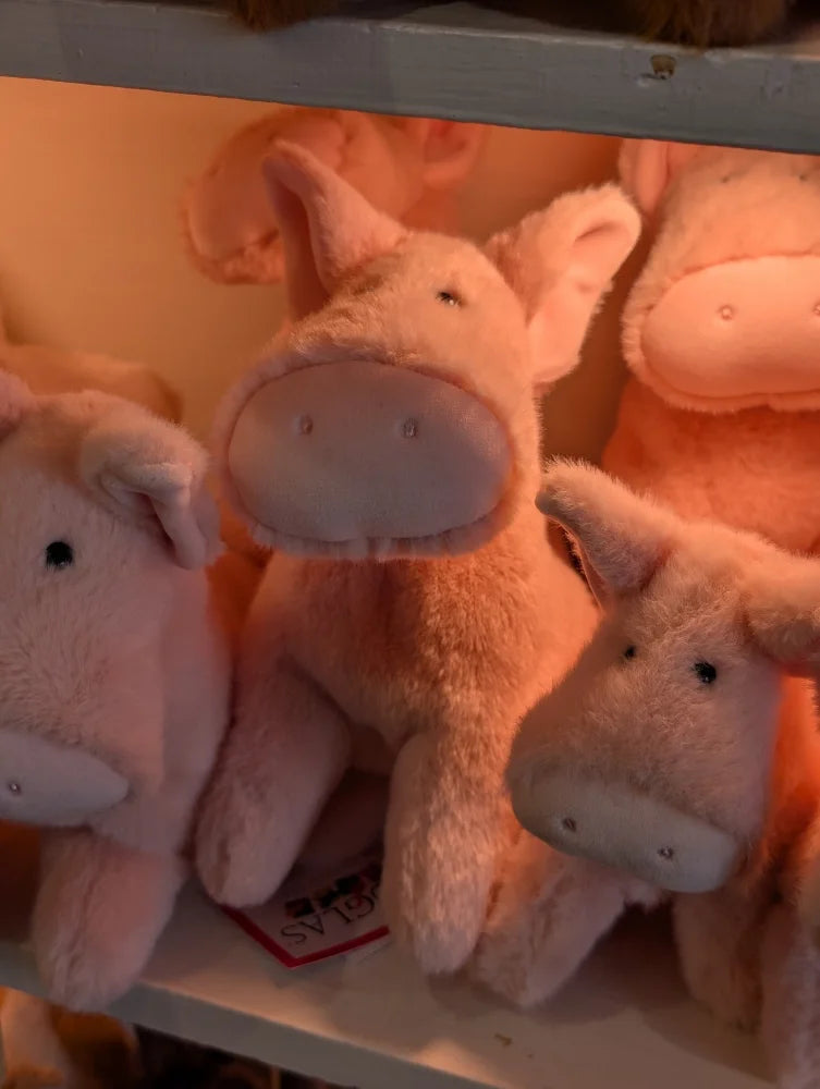 Soft pink plush pig toys with embroidered black eyes and stitched snouts arranged on shelf pink piggies large size