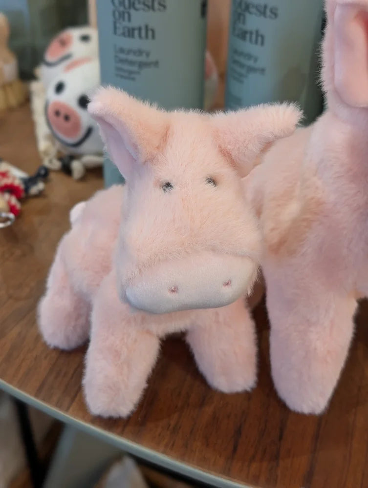 A large size soft pink piggies plush with embroidered eyes and stitched nose sitting on a wooden surface