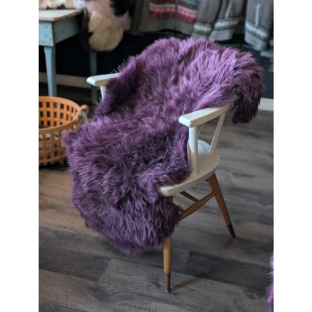 Gorgeous Plum Purple Merino Sheepskin fluffy throw blanket on wooden chair